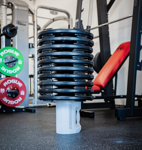 Stack of weight plates on a stand in a gym setting with Rogue weight plates