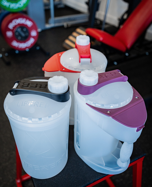 Three bottles with different colored lids on a black surface.